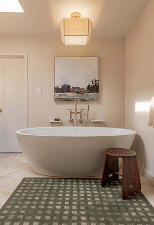 Luxury freestanding soaking tub with natural stone flooring, custom bathroom design, spa-inspired finishes, wall-mounted tub filler, and high-end residential bathroom renovation for a custom home.
