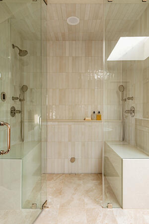 Luxury walk-in shower design featuring frameless glass enclosure, built-in shower bench, full-height tile walls, natural stone flooring, and spa-inspired bathroom renovation details for a custom home remodel.