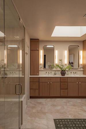 Luxury primary bathroom remodel featuring custom double vanity, frameless glass shower, natural stone tile flooring, skylight, spa-inspired finishes, and high-end residential interior design for a custom home renovation.